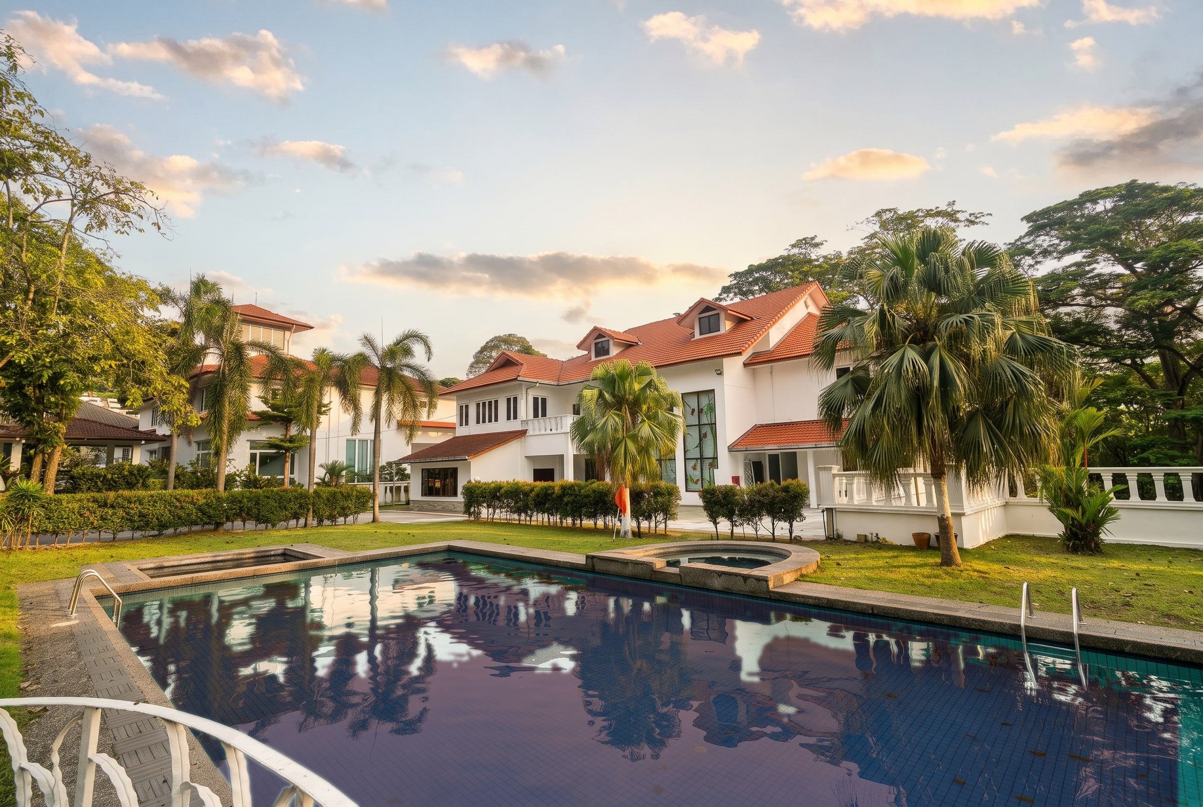Golden-hour light over Trivelle Living's white bungalow, gardens and swimming pool in Country Heights, Kajang