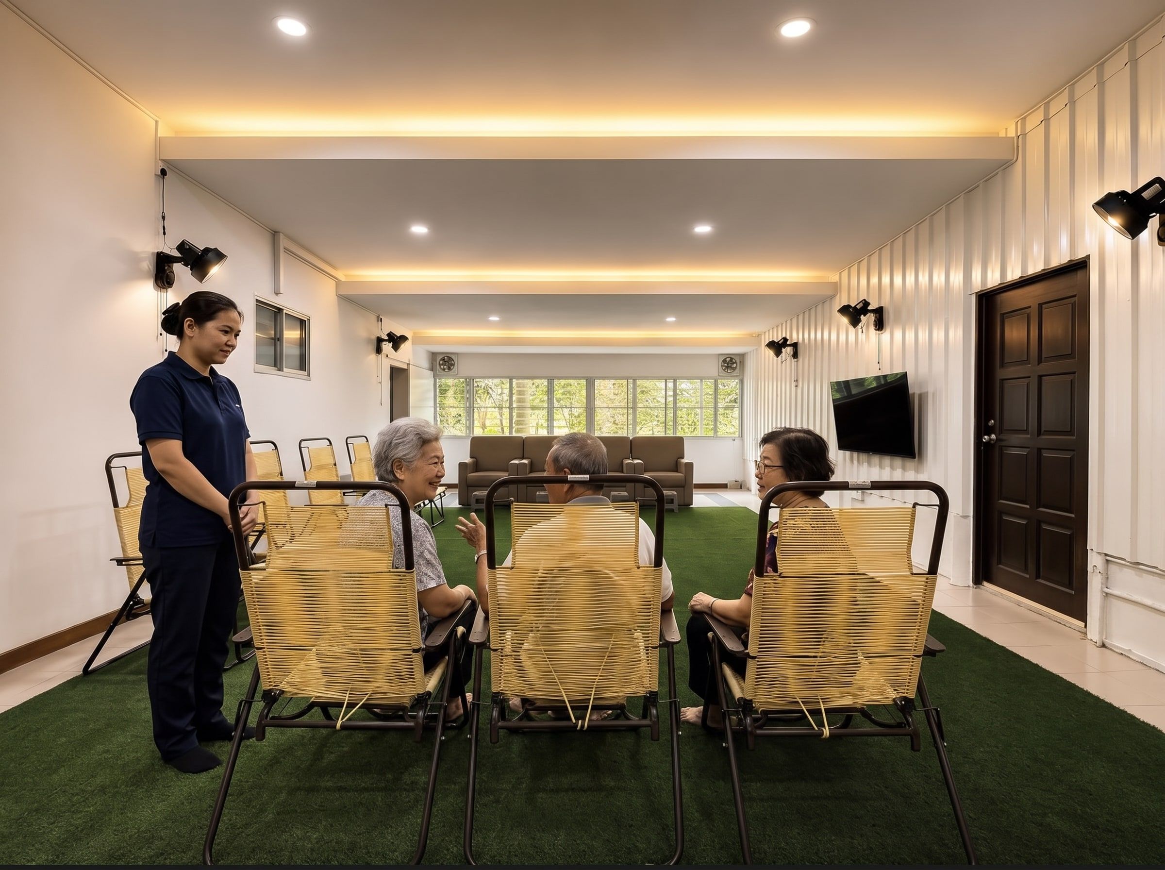 Residents chatting together in the renovated activity lounge with a caregiver nearby