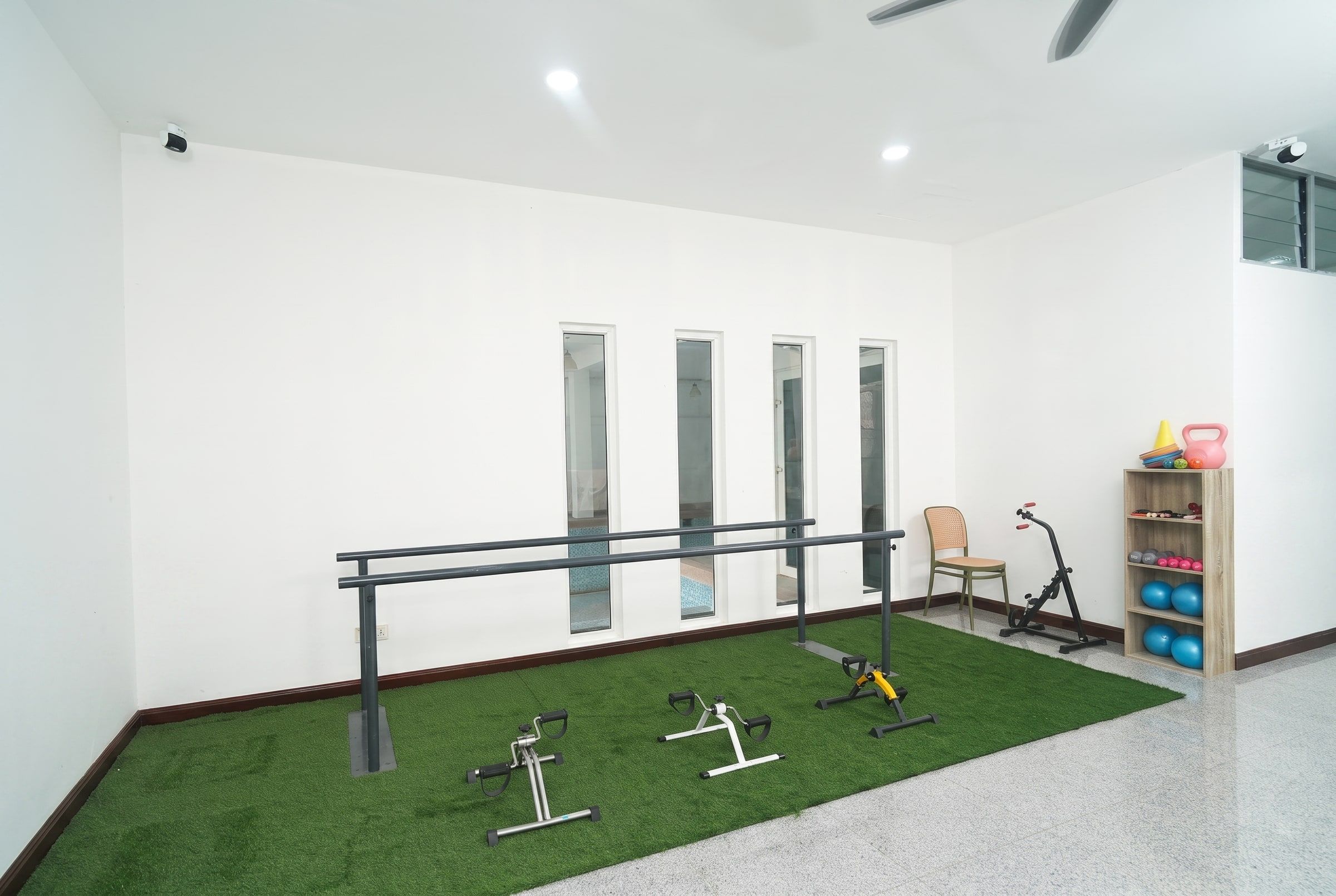 Parallel walking bars, exercise turf and pedal trainers in the physiotherapy room