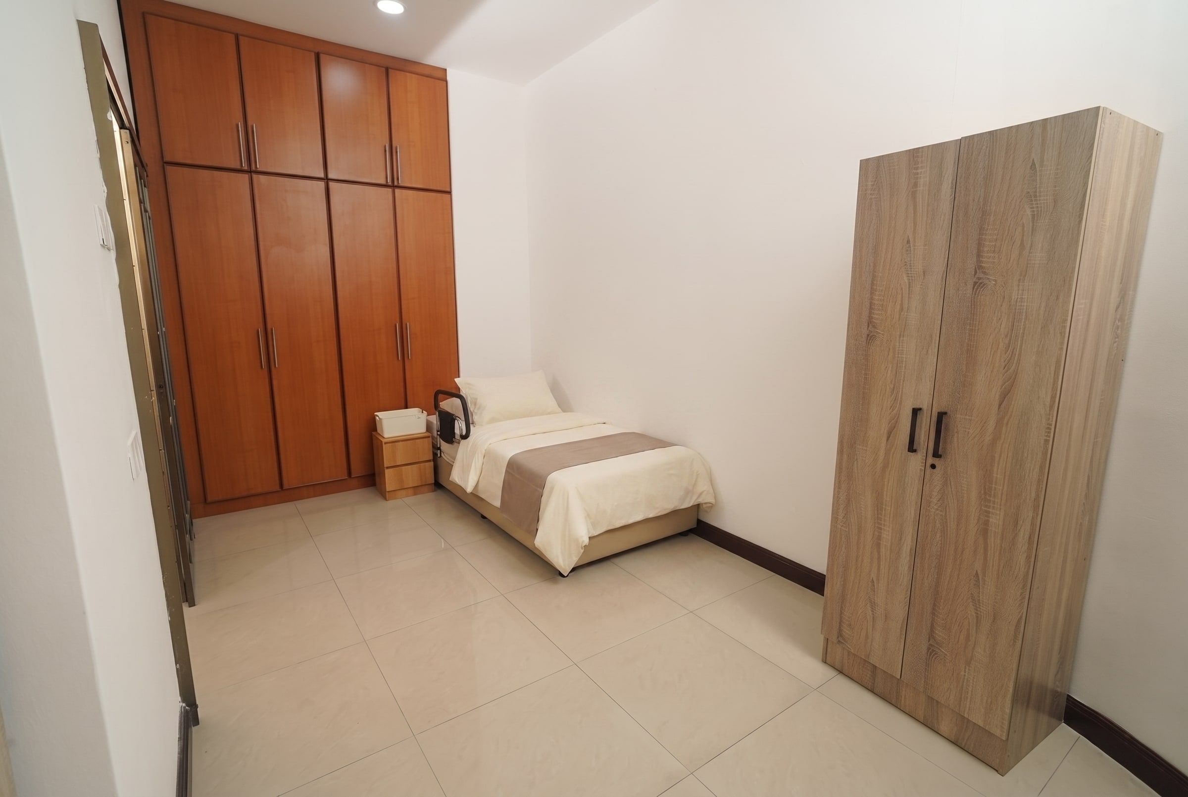 Resident bed beside warm timber built-in cupboards