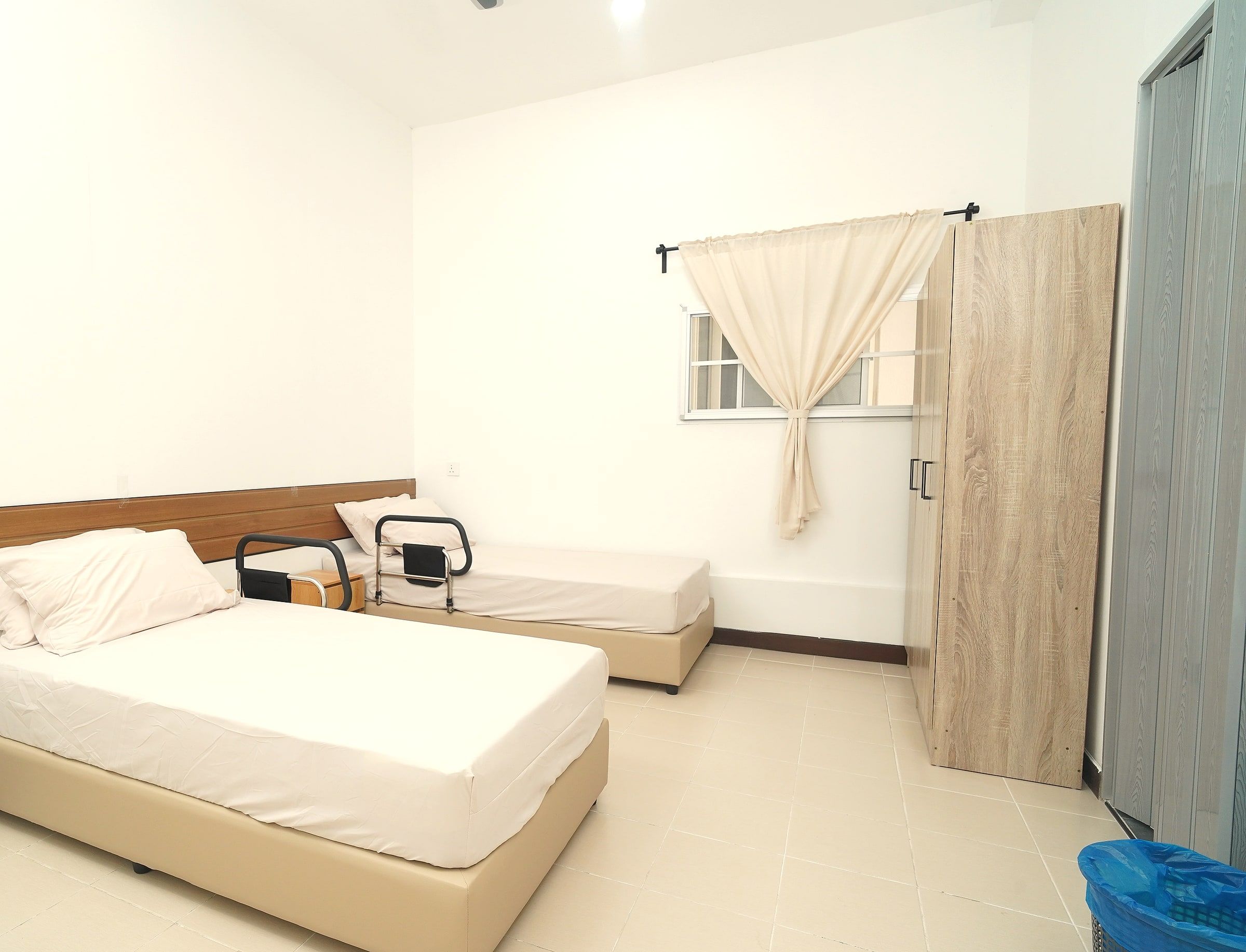 One made-up resident bed beside a curtained window and wardrobe
