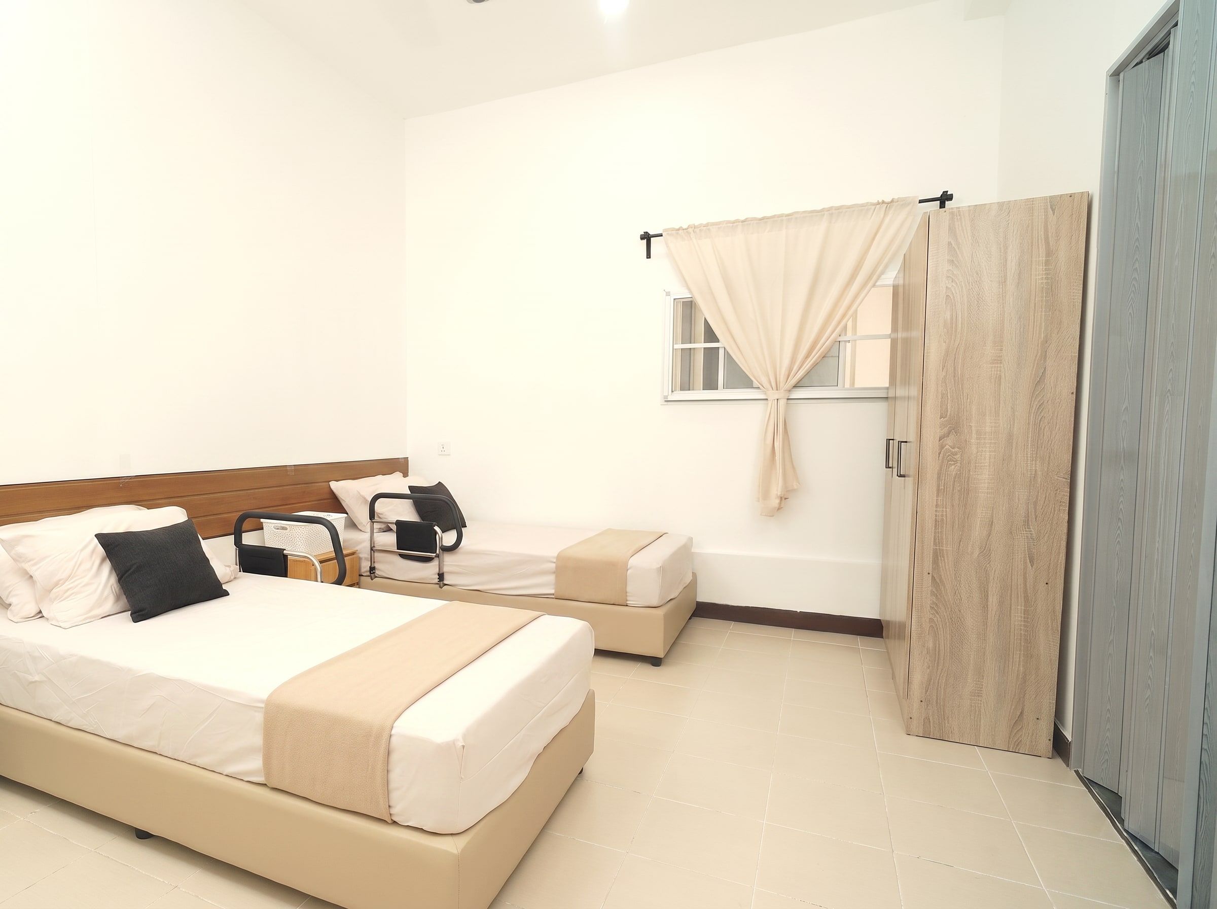 One made-up resident bed beside a curtained window and wardrobe