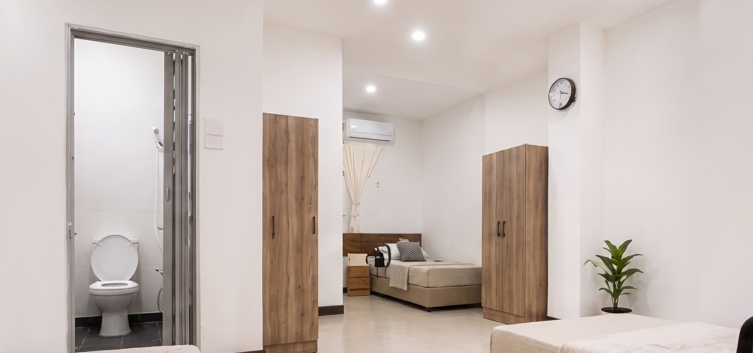 Renovated resident room with beds, wardrobes and the attached private bathroom door open