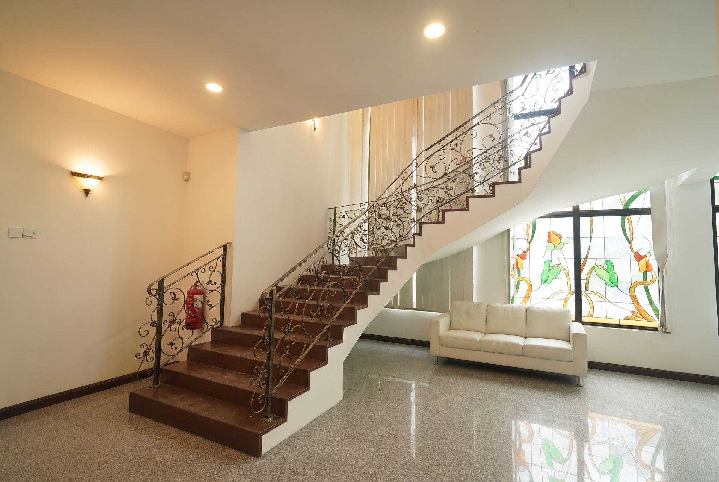 Curved timber staircase beside tall stained-glass windows