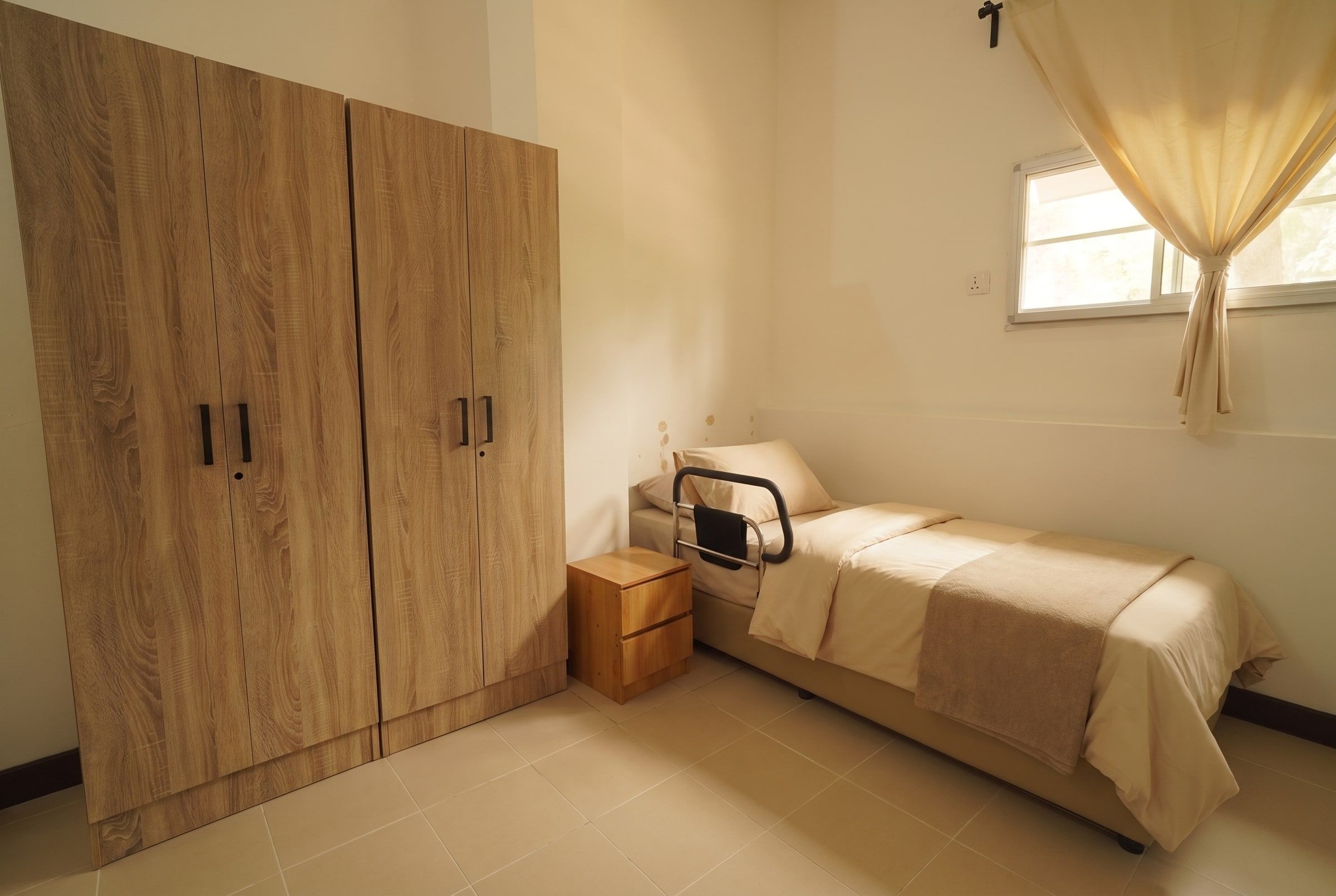 Resident bed with grab rail beside full-height wardrobes