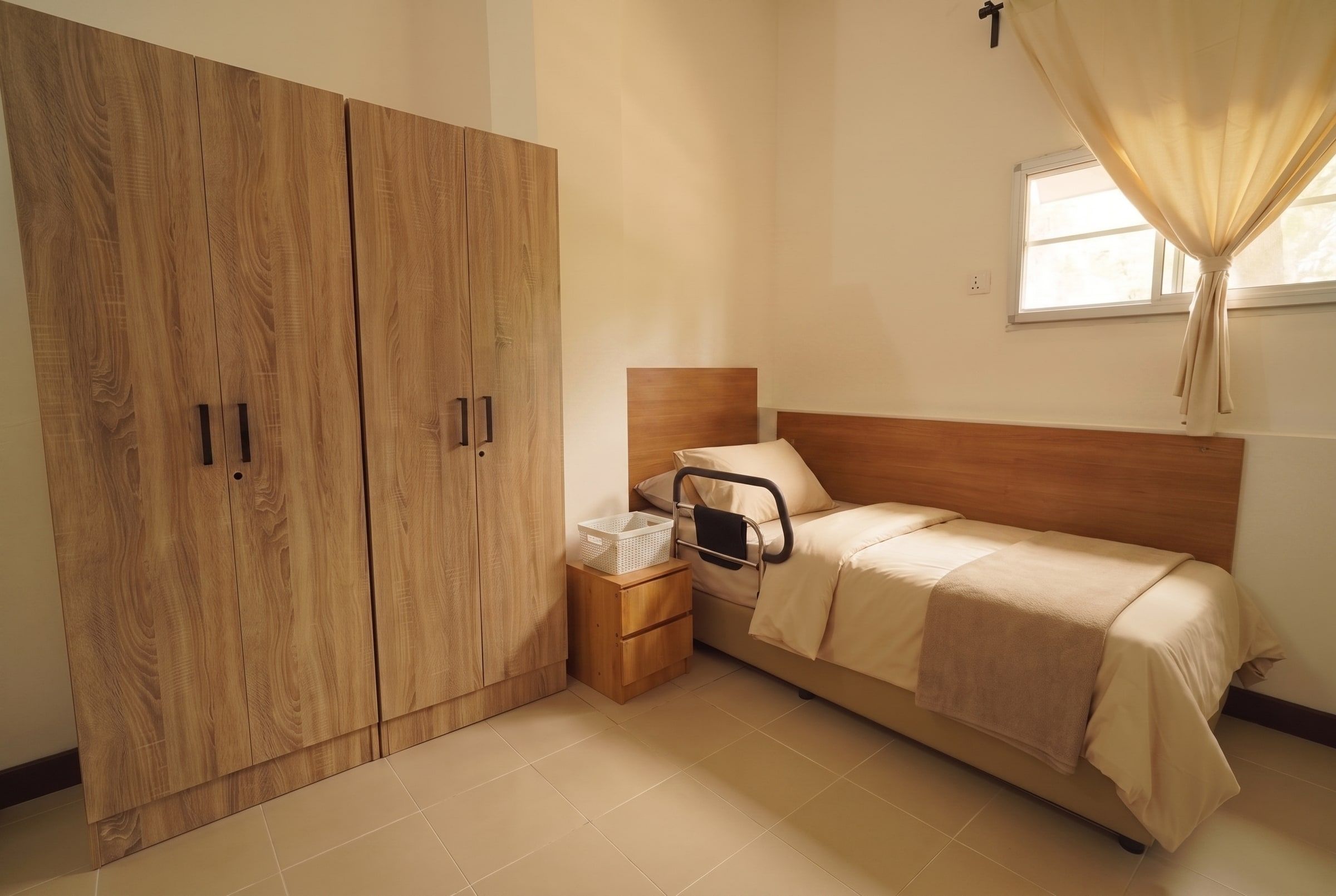 Resident bed with grab rail beside full-height wardrobes